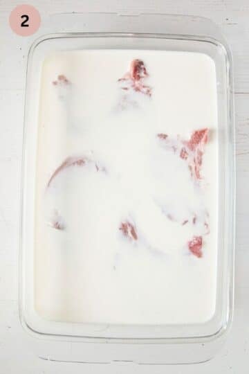 pork chops brining in lots of milk in a large baking dish.