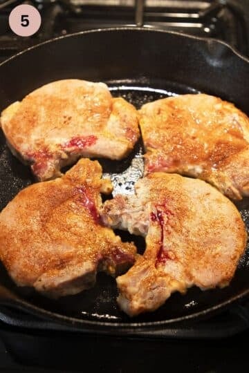 frying pork chops in a skillet on the first side.