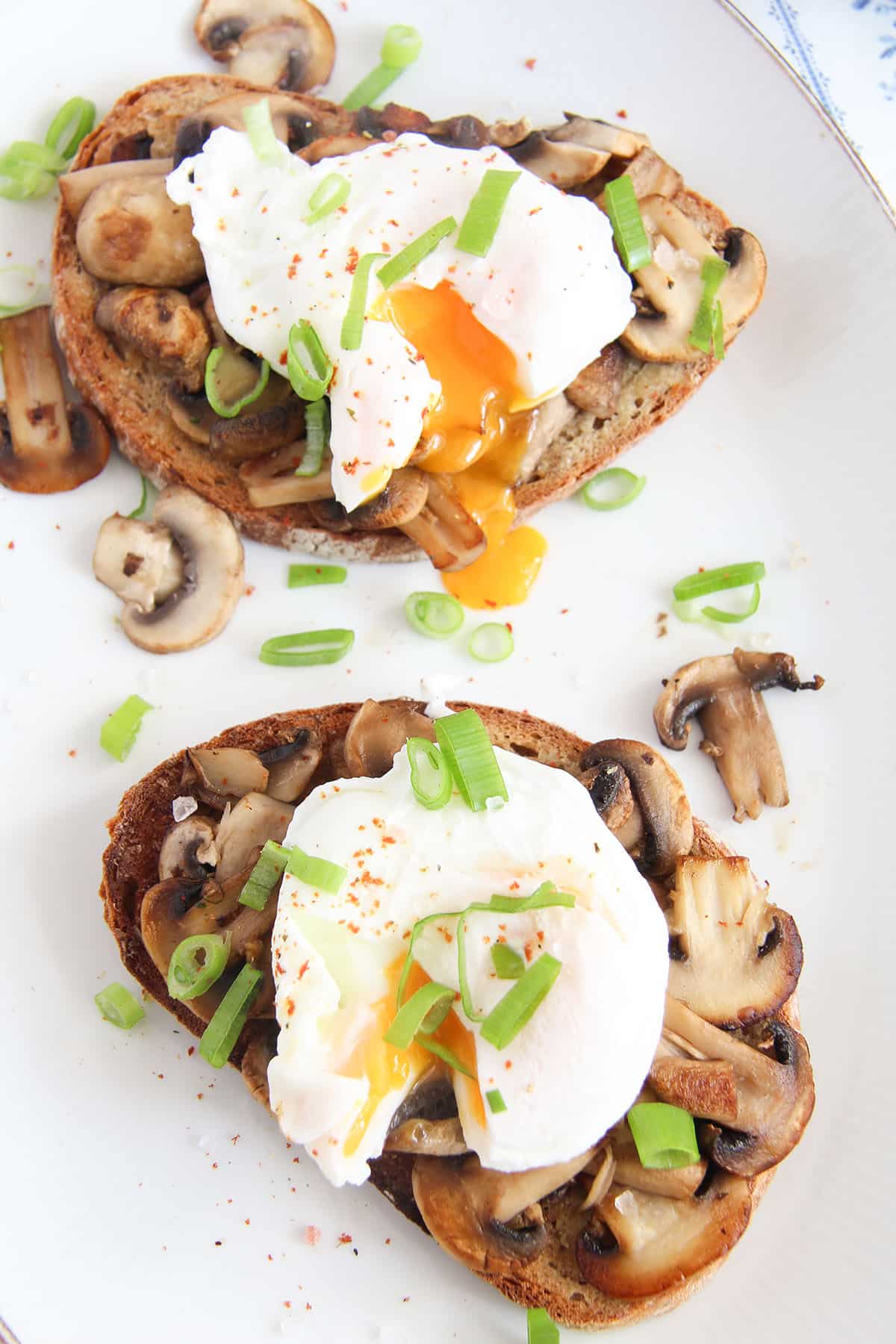two sourdough toasts with mushroom and runny poached eggs.