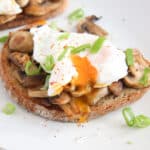 mushroom toast with poached egg on top sprinkled with green onions and pepper.