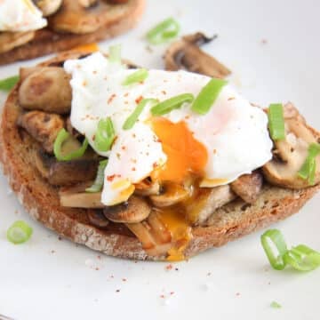 mushroom toast with poached egg on top sprinkled with green onions and pepper.