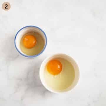 two cracked eggs in ramekin bowls before poaching.
