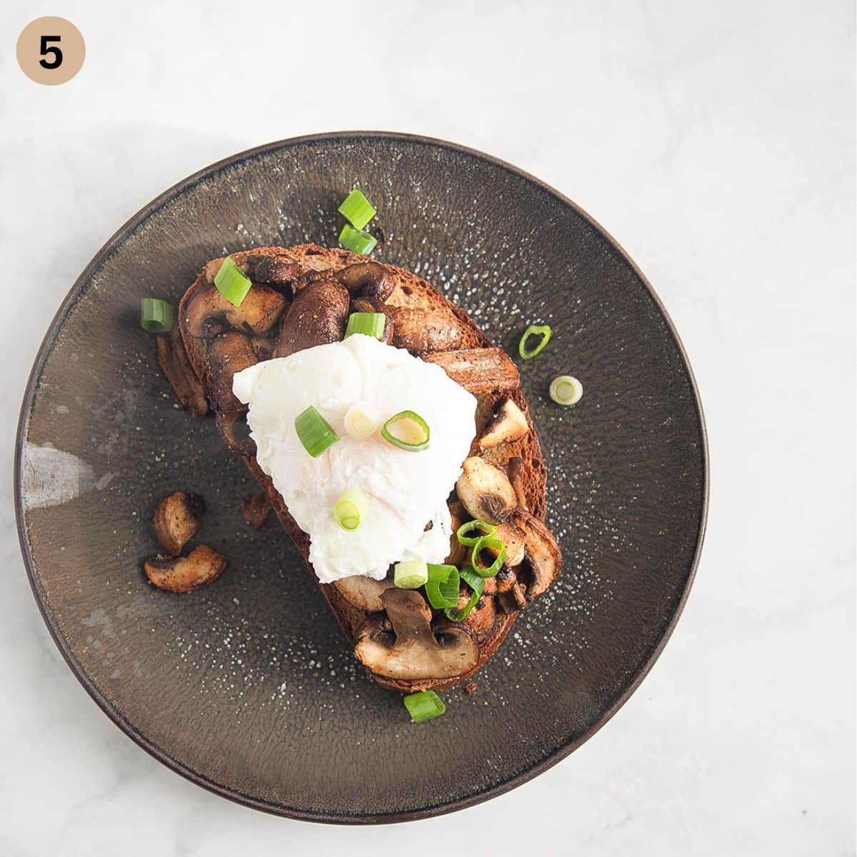 topping sourdough bread slice with mushrooms, poached eggs and chopped green onions.
