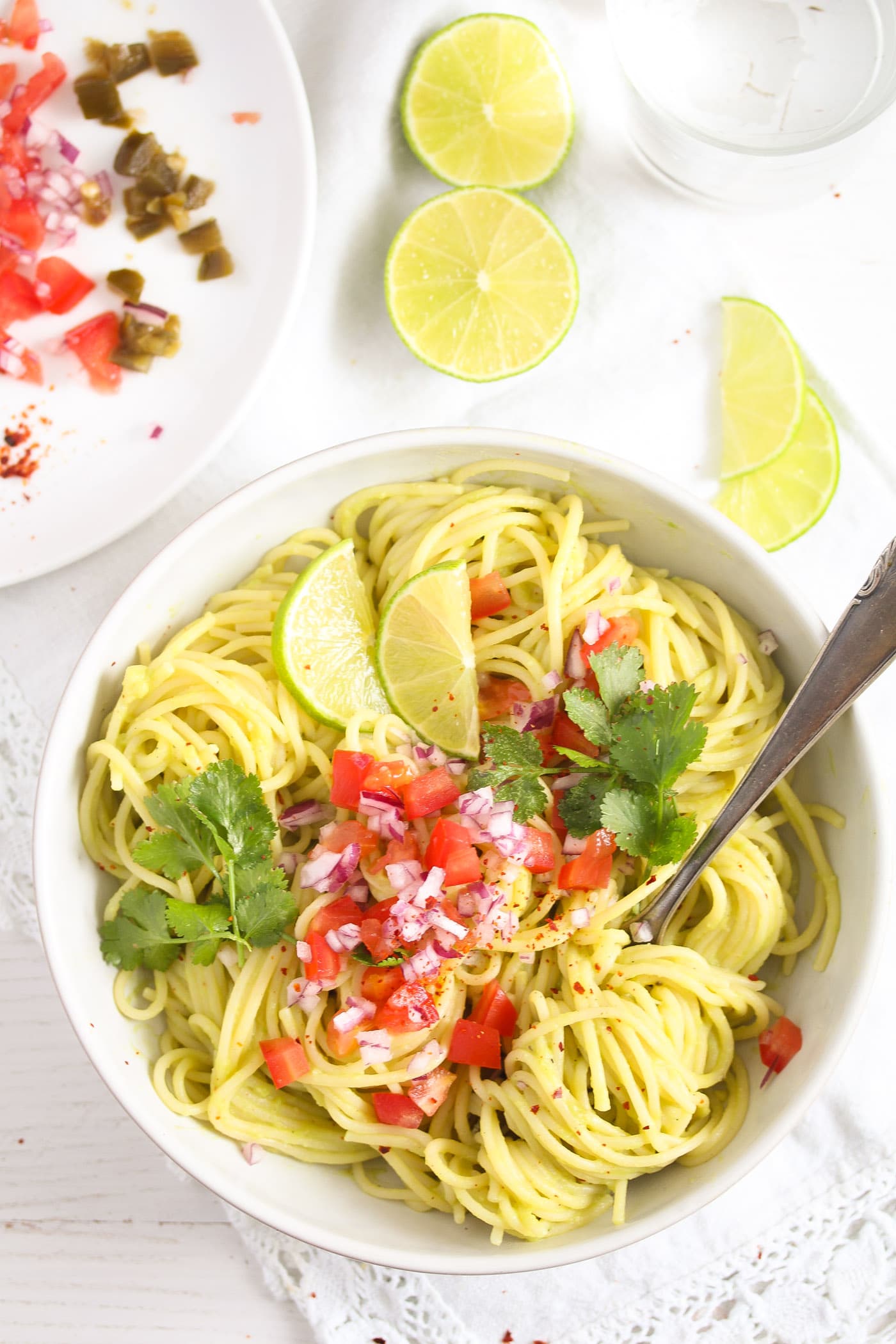 creamy guacamole pasta with lime wedges seen from above