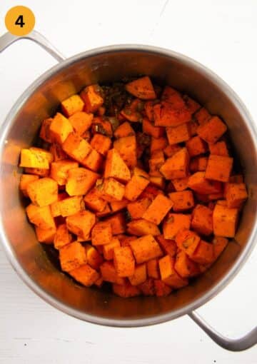 sauteing sweet potato and pumpkin cubes in a pot to make soup.