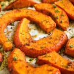 close up of roasted pumpkin wedges sprinkled with parsley.