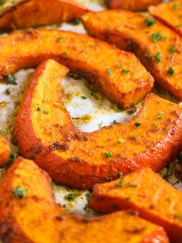 close up of roasted pumpkin wedges sprinkled with parsley.