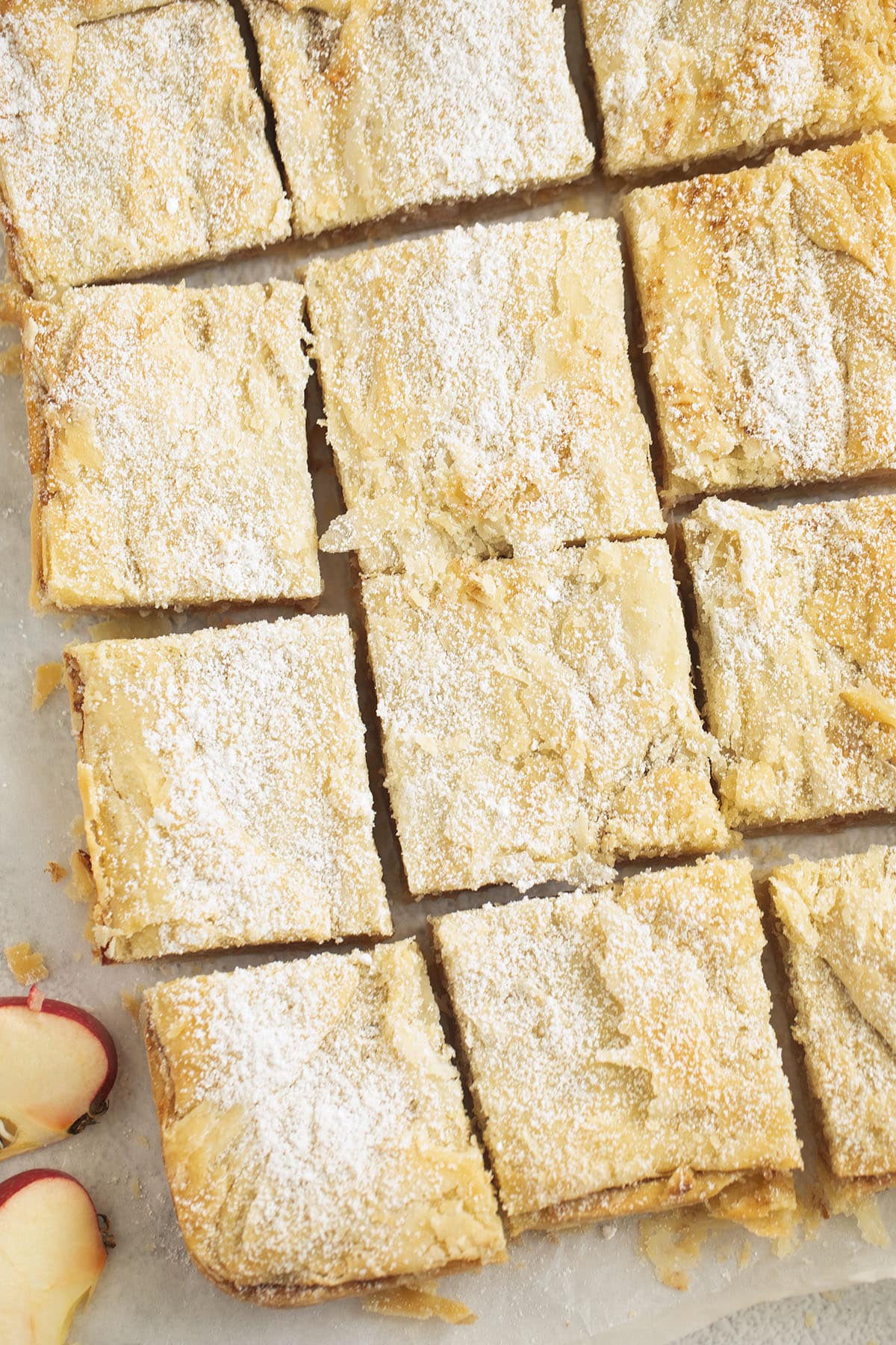 romanian apple pie cut into squares and sprinkled with powdered sugar.