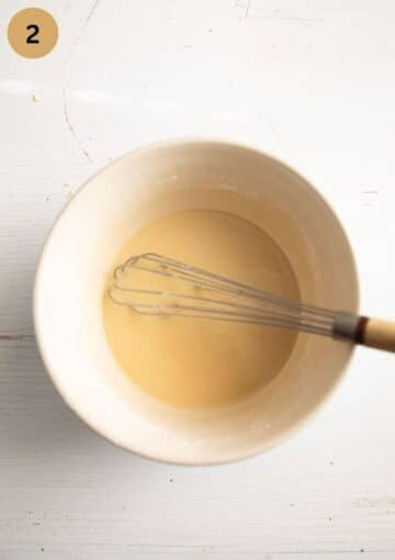 stirring flour and oil with a egg whisk in a bowl.