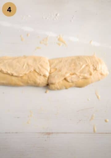 pie dough rolled in a large sausage and cut into two halves on the working surface.