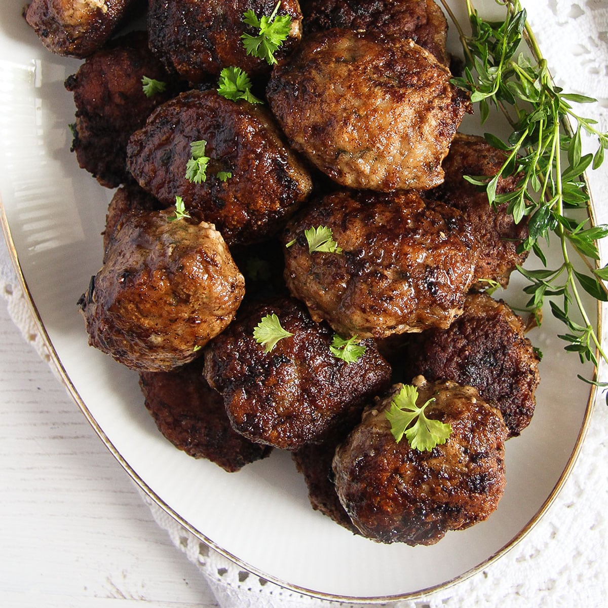 romanian meatballs and fresh thyme sprigs on a platter.