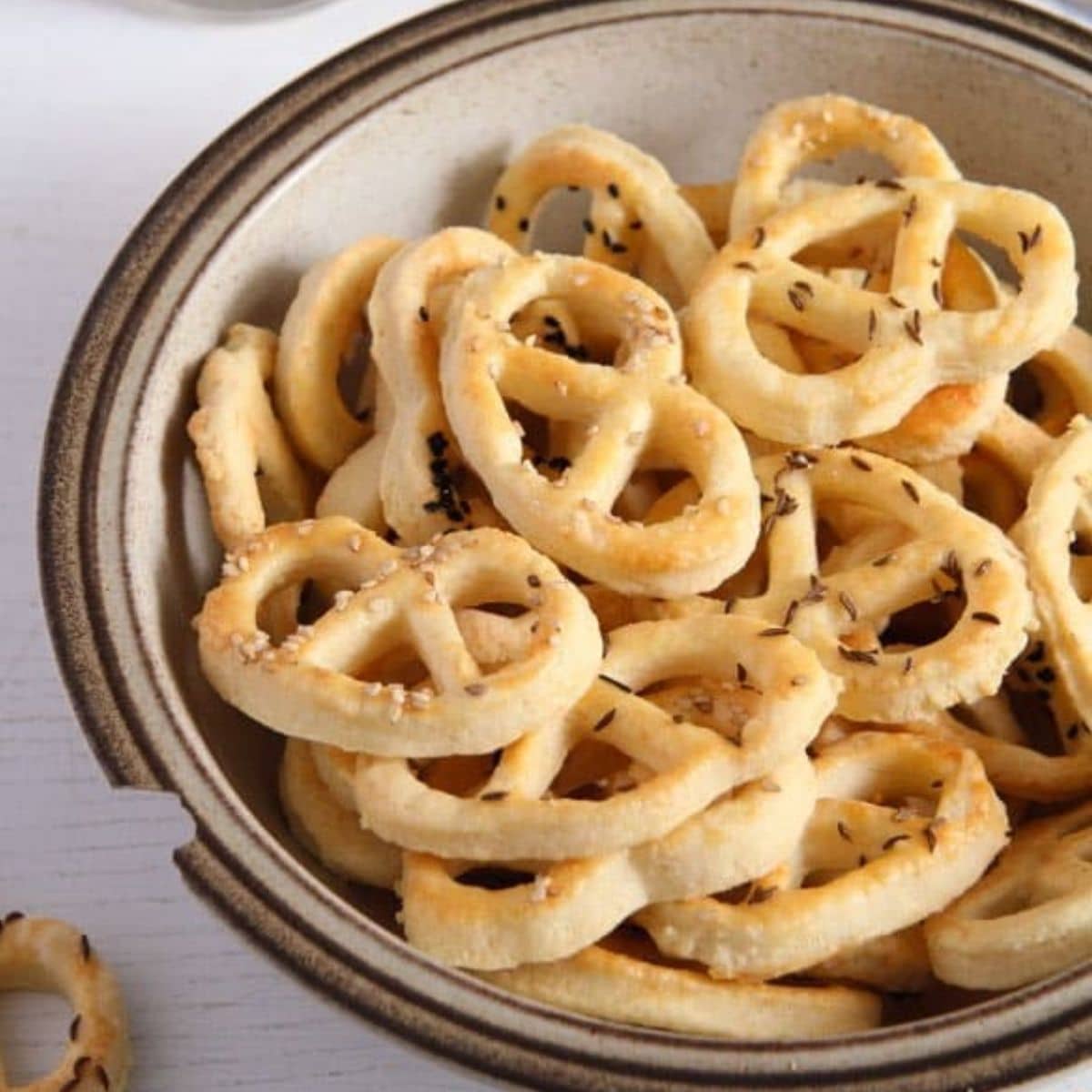 bowl with many romanian preztels or covrigei sprinkled with caraway seeds.