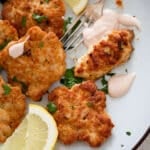 russian chicken patties, lemon wedges, dip and a fork on a plate.