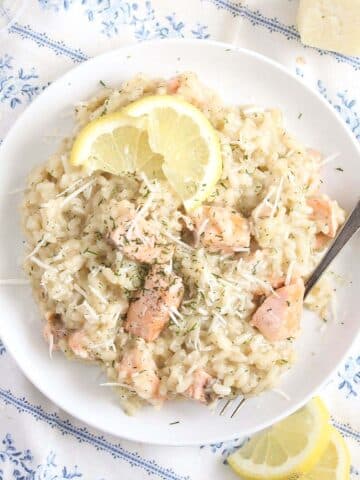 salmon risotto with dill and parmesan on a white plate