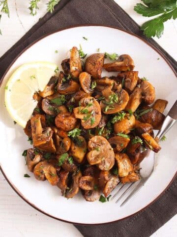air fryer mushrooms served with lemon wedgeds on a white plate