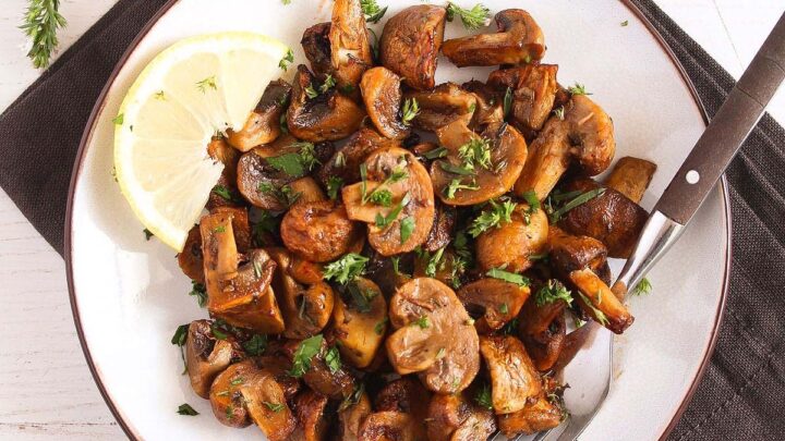 air fryer mushrooms served with lemon wedgeds on a white plate.