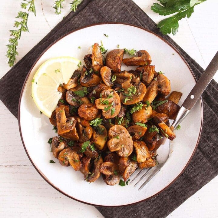 air fryer mushrooms served with lemon wedgeds on a white plate