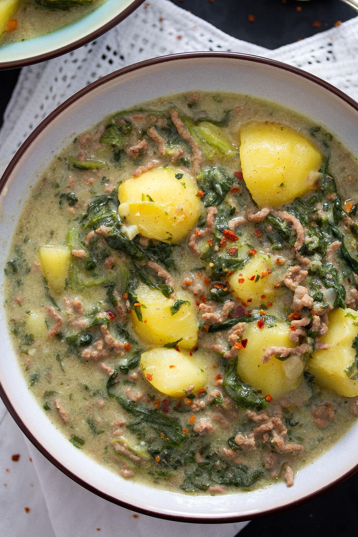 chunky potatoes, ground beef, and spinach in curry sauce in a bowl.