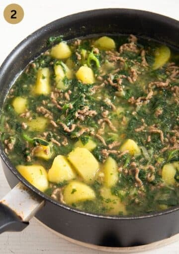 cooking curry with ground beef, chunky potatoes and spinach in a saucepan.