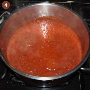 simmering plum jam in a large pot on the stovetop.