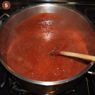 stirring plum butter with a wooden spoon in a pot.
