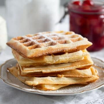 a staple of german waffles sprinkled with powderes sugar on a small plate.