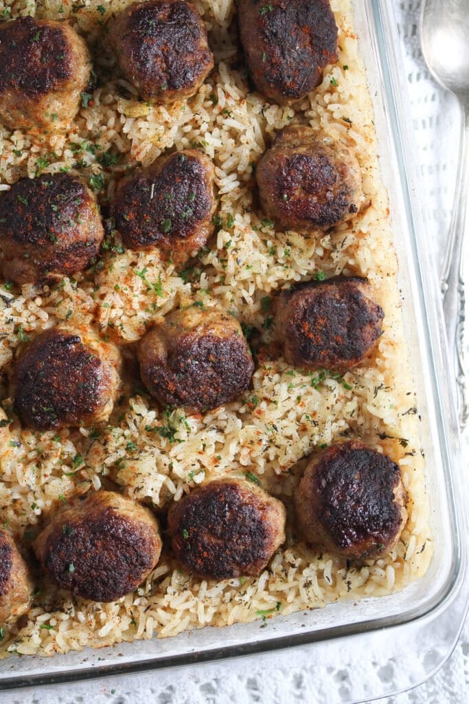 brown meatballs served on cooked long grain rice in a baking dish