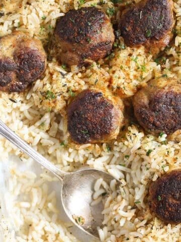meatballs and rice being served with a spoon