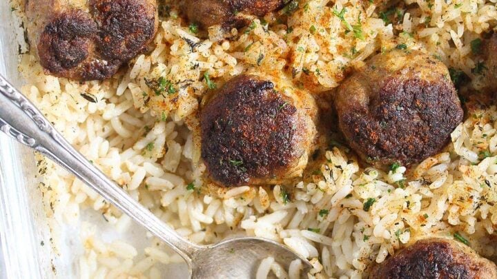 meatballs and rice being served with a spoon directly from the baking dish.