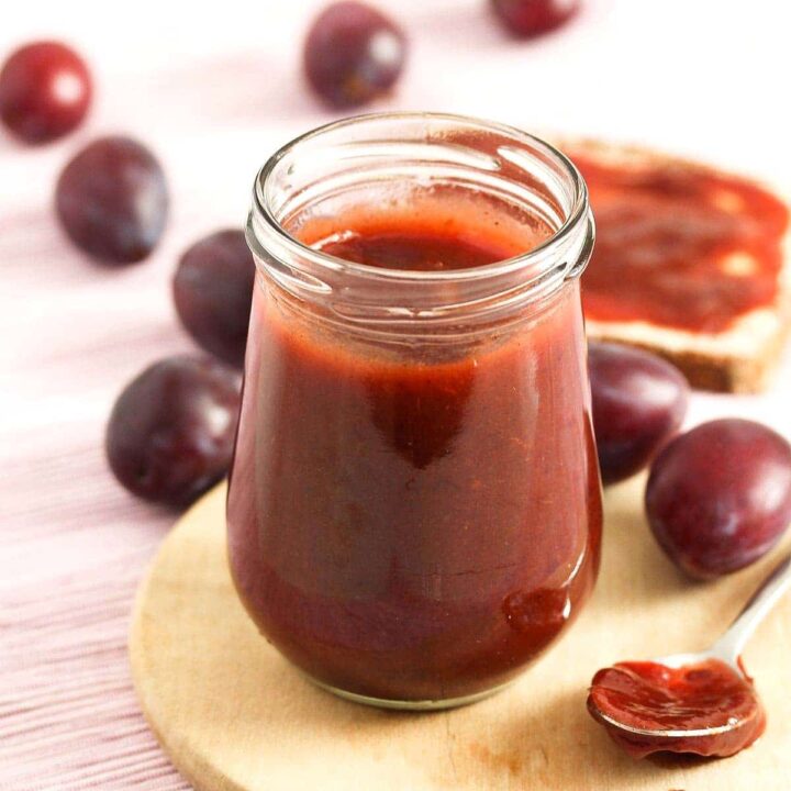 pflaumenmus in a small jar with plums on the table