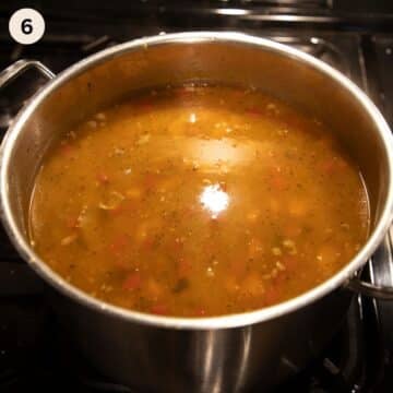 simmering soup with pork ribs, beans and veggies in a large pot.