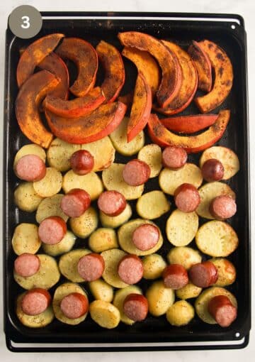 baked pumpkin wedges, potato slices and sausages on a baking tray.