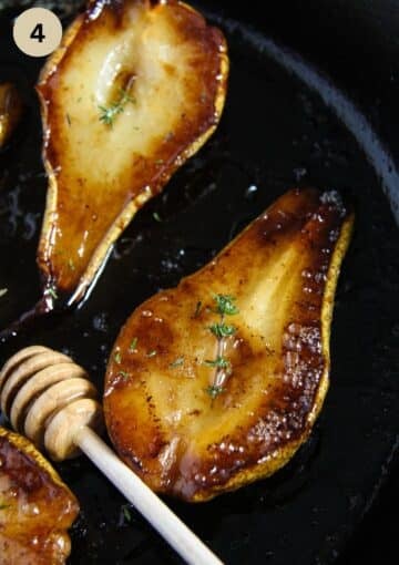 two caramelized pears drizzled with honey in a skillet.