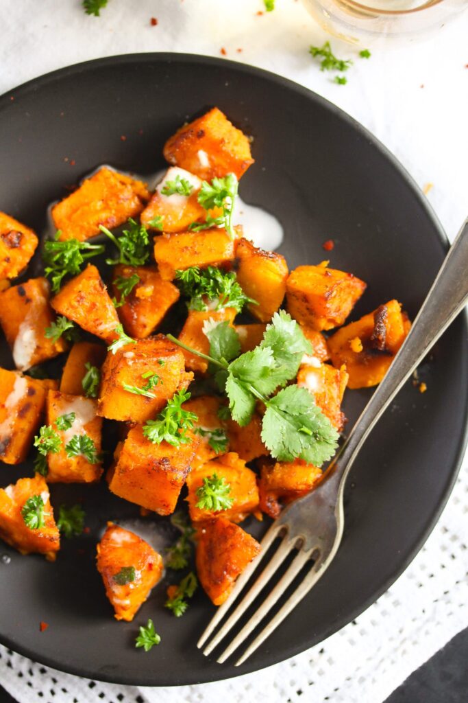 sauteed sweet potatoes on a large brown plate with a vintage fork