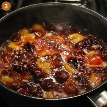 halved plums stewing in a large saucepan on the stovetop.