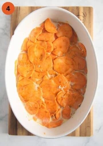 layers of thin sweet potato slices in an oval baking dish for making gratin.