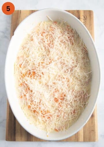 unbaked sweet potato dauphinoise sprinkled with lots of parmesan in an oval baking dish.