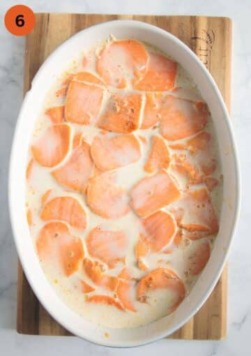 layering sweet potato slices with cream and milk mixture in a baking dish.