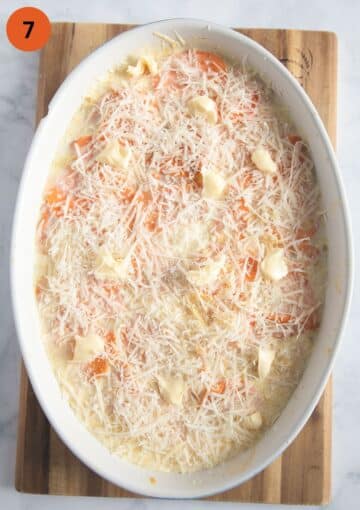 unbaked sweet potato dauphinoise sprinkled with parmesan and dotted with butter in a baking dish.