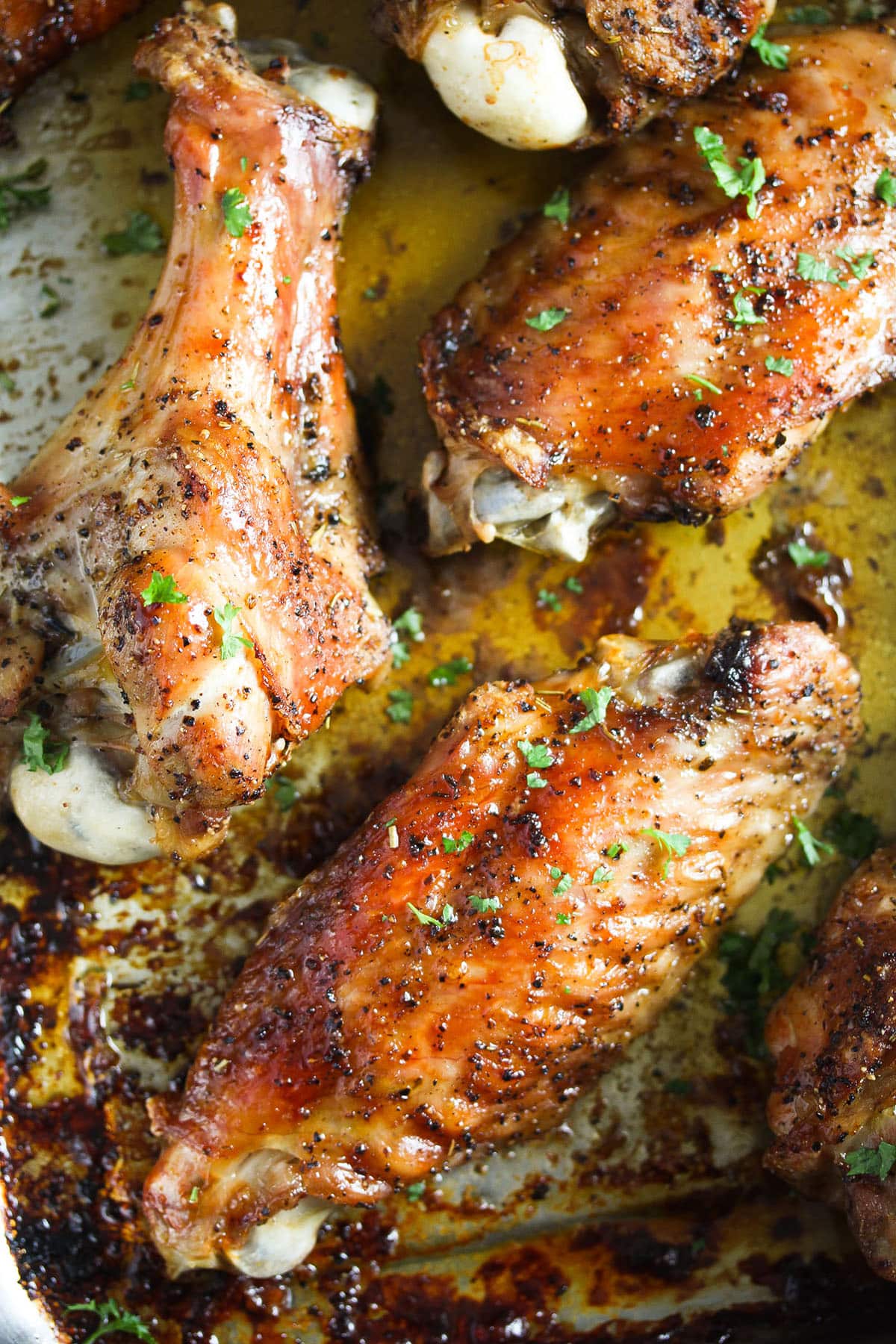 golden brown crispy roasted turkey wings in a pool of cooking juices.