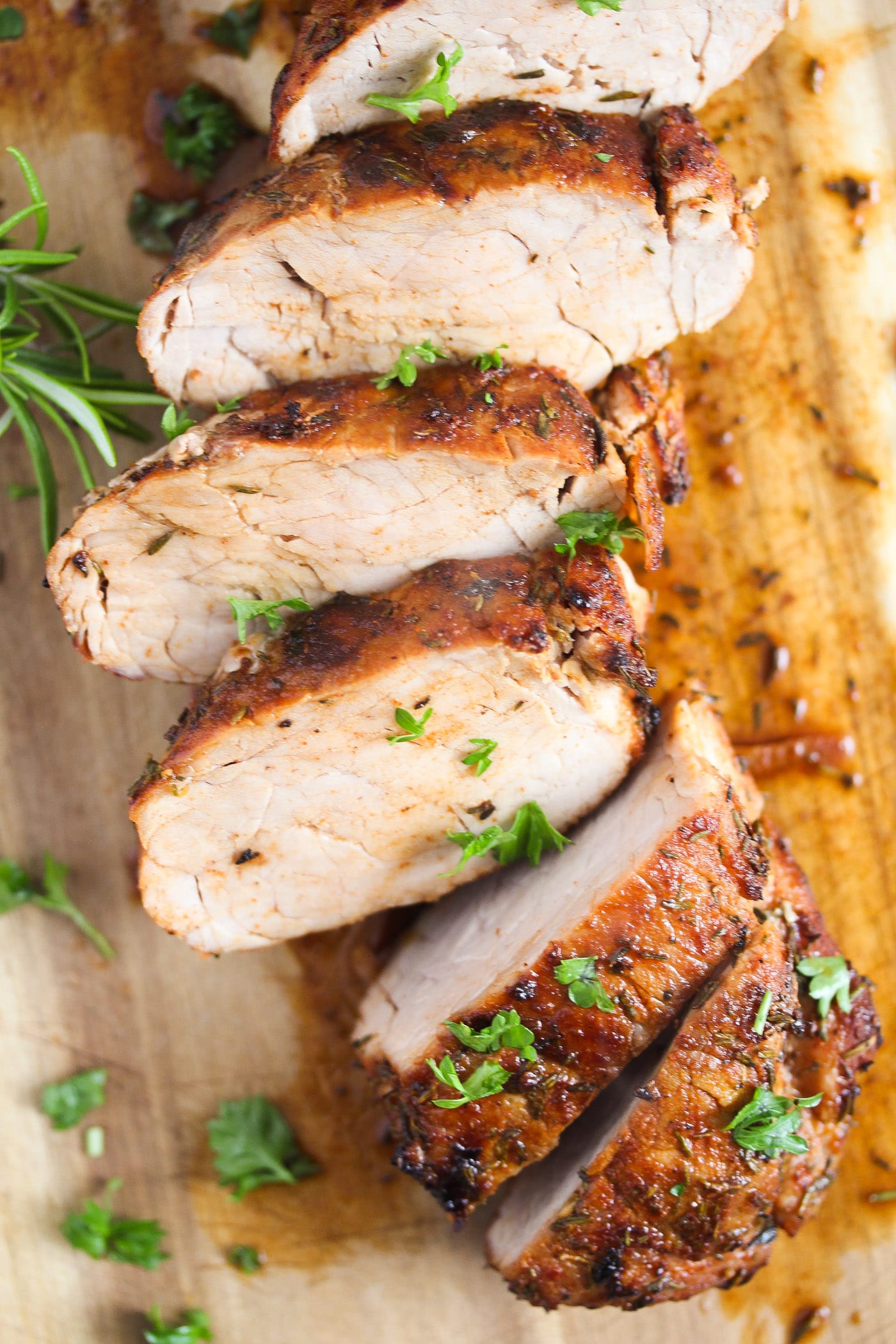 slice pork tenderloin sprinkle with fresh parsley on a wooden board