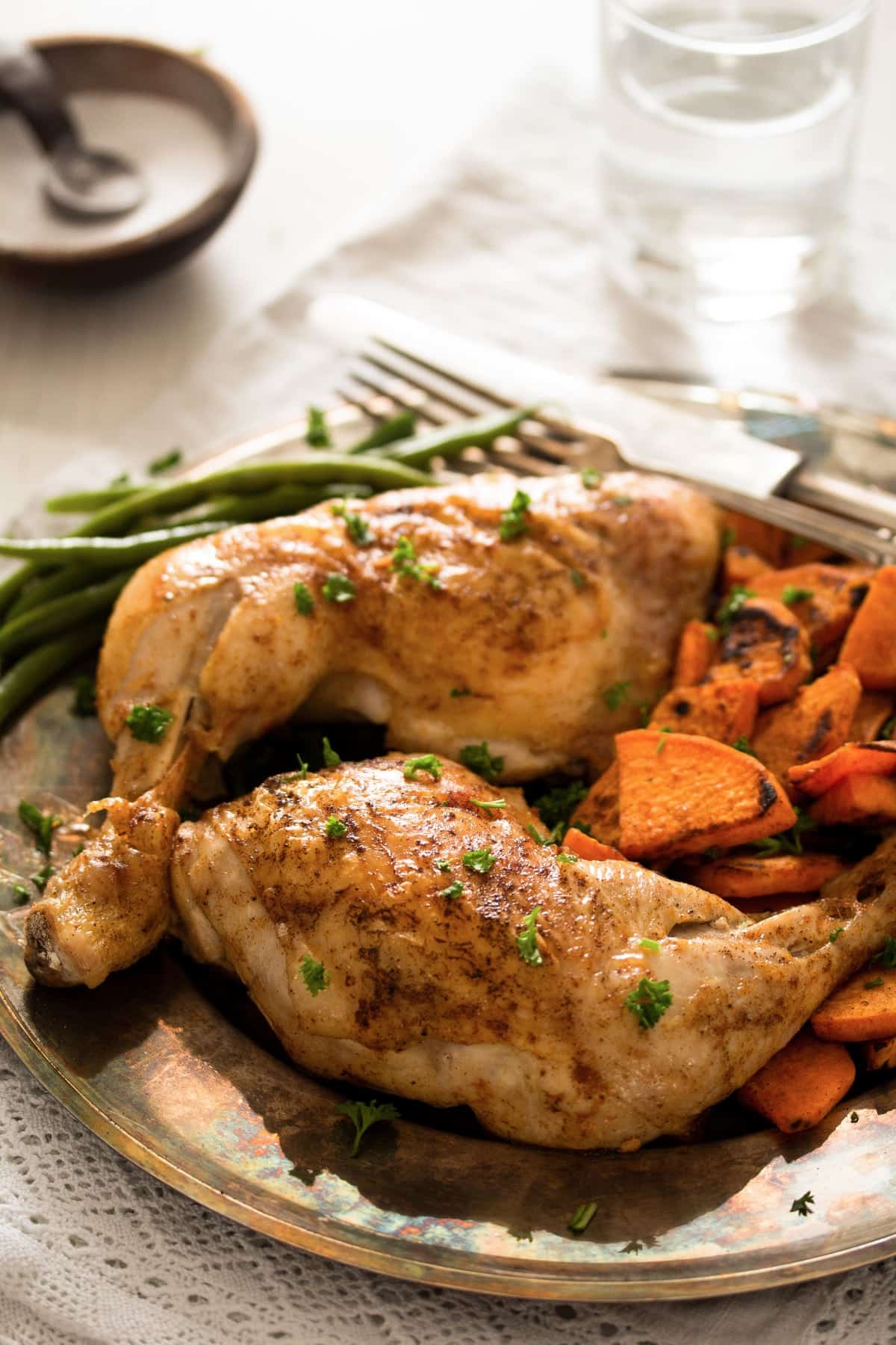 plate with two chicken quarters baked in the oven, sweet potatoes and green beans.