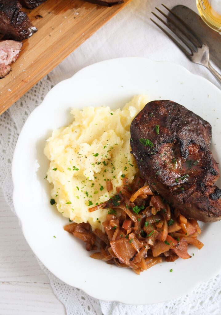 turkey liver served with mashed potatoes and onion apple sauce on a white plate