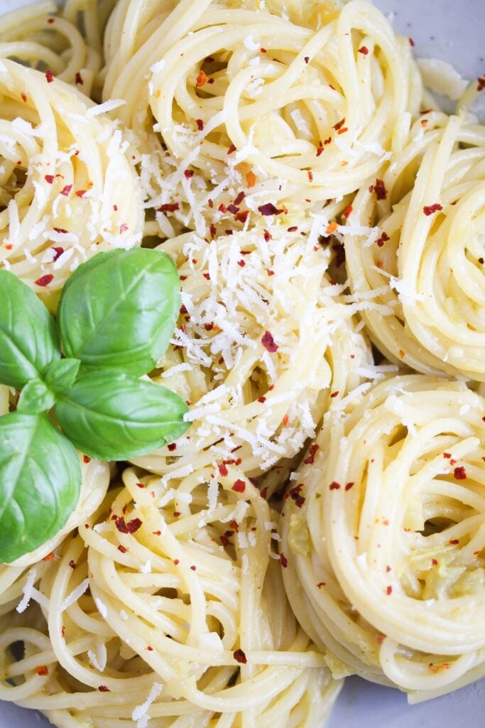 close up rolled spaghetti sprinkled with parmesan and chili flakes