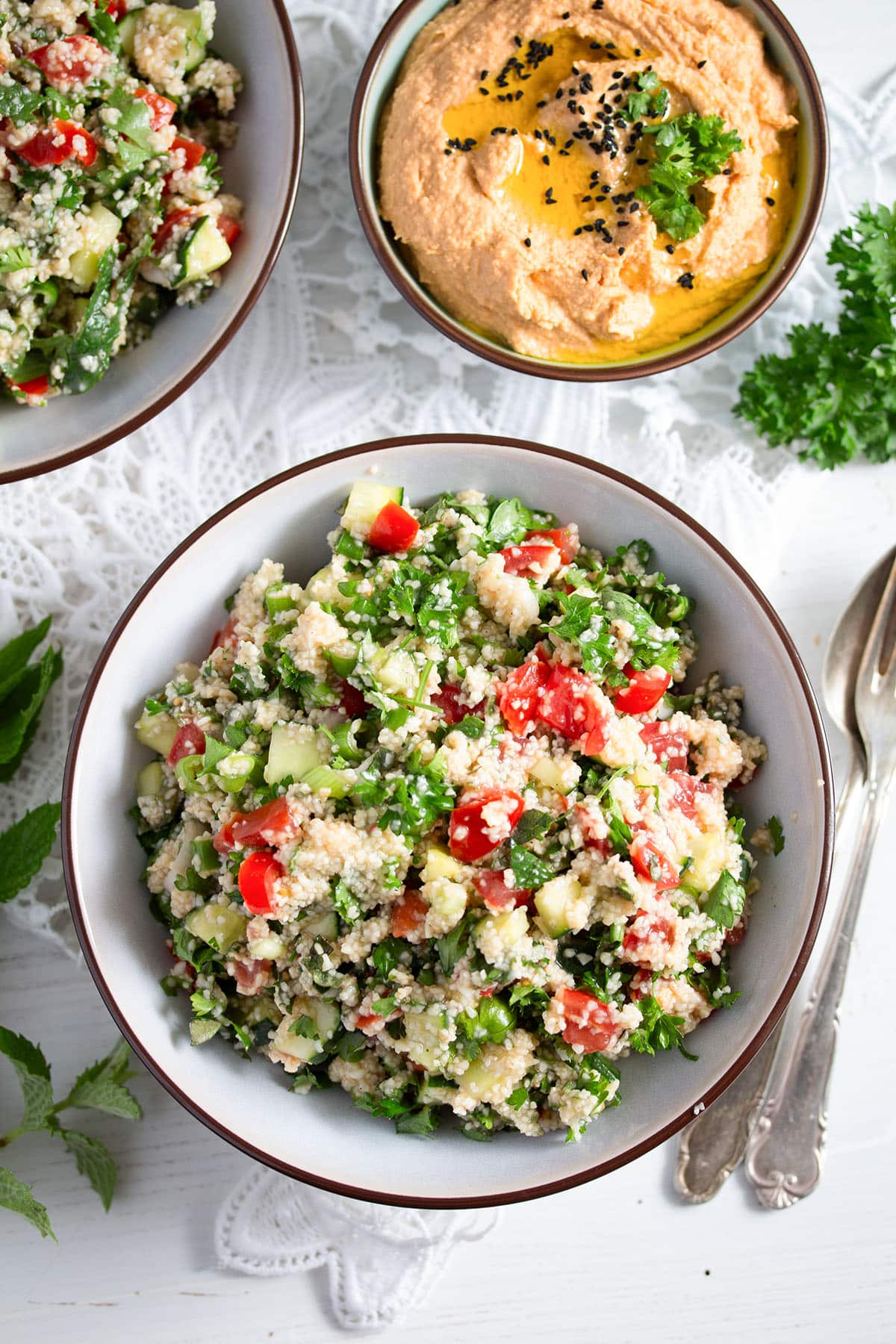bowls with tabbouleh and hummus on the table.