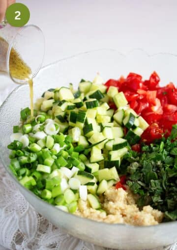 pouring dressing over mediterranean salad with parsley and cucumbers.