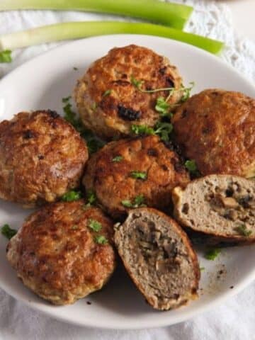 polish mushroom-stuffed meatballs on a white plate, one is cut to show the filling.