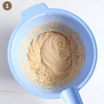 mixing eggs and brown sugar in a blue bowl for making batter for pumpkin fruitcake.