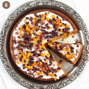 pumpkin fruitcake glazed and sprinkled with chopped dried fruit on a platter.