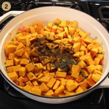 raw pumpkin pieces and lots of spices in a pot before cooking.